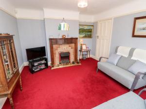 a living room with a red carpet and a fireplace at Goodrest in Verwood