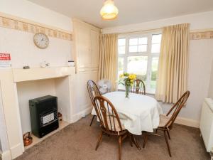 a dining room with a table with a vase of flowers on it at Goodrest in Verwood