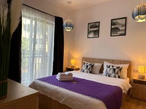 a bedroom with a bed with purple sheets and a window at Lipatti 15 Apartments by GLAM LUXURY in Timişoara