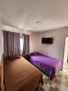1 dormitorio con 2 camas y TV en la pared en El Pescador, en Iquique