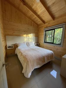 a bedroom with a bed in a wooden cabin at Cabañas Altos del Bosque in Licán Ray