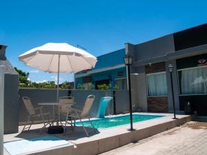 una mesa con sombrilla junto a la piscina en Cada com piscina 50mts da praia!, en Itapoa