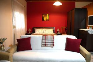 a bedroom with a bed with red walls and a couch at Cottage Lina in Edessa