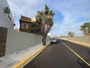 un coche aparcado al lado de una calle con una palmera en Suites- Salinas en Salinas