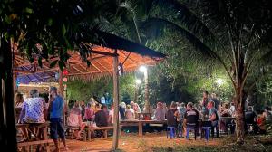 a group of people sitting at tables in a garden at Groovy Bungalows Koh Phayam in Ko Phayam