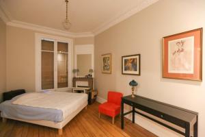 1 dormitorio con 1 cama y 1 silla roja en Pretty cocoon on the banks of the Seine en París