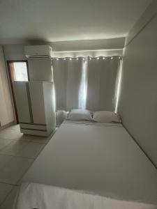 Habitación blanca pequeña con cama y nevera en Residencial Carajás en Goiânia