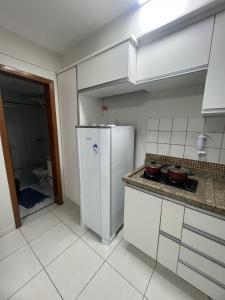 cocina blanca con nevera y aseo en Residencial Carajás, en Goiânia