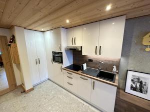 a kitchen with white cabinets and a sink at TIGNES VAL CLARET A LA CONQUETE DES SOMMETS 116 in Tignes
