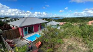 a small pink house with a swimming pool at La villa Jalna Grenadine deux chambres et piscine privée in Les Trois-Îlets
