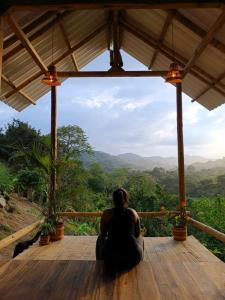 una donna seduta su un ponte di legno che guarda le montagne di La Mona Eco Cabins a Palomino