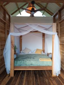 La Mona Eco Cabins في بالومينو: غرفة نوم بسرير مع مظلة