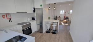 a kitchen with white counters and stools in it at Casa do Pescador in Lagoa