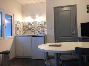 een kamer met een tafel en een keuken met een deur bij Studio des champs in Montélimar