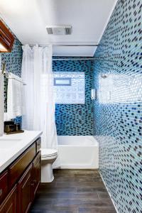 uma casa de banho com banheira, WC e azulejos azuis em Antlers - A Birdy Vacation Rental em San Antonio