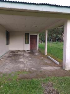 ein leeres Gebäude mit roter Tür und Gras in der Unterkunft Habitacion en Bijagua in Bijagua