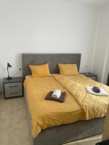 ein großes Bett mit gelber Bettwäsche und Handtüchern darauf in der Unterkunft ViVo Beach Apartment in Durrës