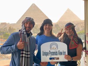 eine Gruppe von Menschen, die ein Schild vor den Pyramiden halten in der Unterkunft Unique Pyramids View INN in Kairo