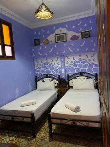 two beds in a room with blue walls at dream house sebanine in Chefchaouen
