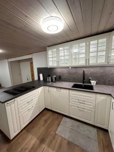 a kitchen with white cabinets and a sink in it at Joy Stugan Näsfjället in Sörsjön