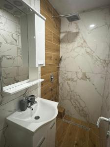 ein weißes Bad mit einem Waschbecken und einer Dusche in der Unterkunft Apartmani Andjela in Jahorina