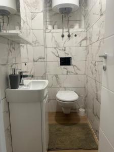 a white bathroom with a toilet and a sink at Apartmani Andjela in Jahorina