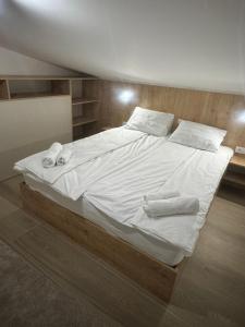 a large bed with white sheets and towels on it at Apartmani Andjela in Jahorina