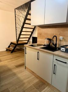 a kitchen with white cabinets and a sink and a staircase at Apartmani Andjela in Jahorina