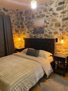 a bedroom with a bed and a stone wall at Adeste to Lasithi Luxury Apartment in Mésa Lasithákion