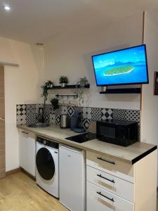 cocina con TV en la pared en Velours & Balnéo, en Saint-Nazaire