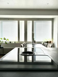 ein Wohnzimmer mit einem Tisch und einigen Fenstern in der Unterkunft Turku Central Luxury Modern Cozy Flat 69m2 in Turku