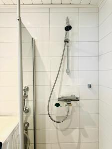 prysznic z wężem w wyłożonej białymi kafelkami łazience w obiekcie Turku Central Luxury Modern Cozy Flat 69m2 w mieście Turku