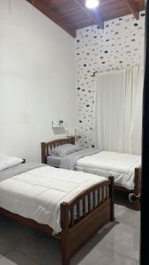 3 Betten in einem Zimmer mit weißen Wänden in der Unterkunft Casa ALGABELLA in Ángeles