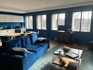 Sala de estar azul con sofá azul y mesa en Appartement spacieux 2 chambres avec vue sur le Rhône et parc, en Caluire-et-Cuire
