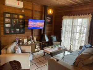 uma sala de estar com uma televisão de ecrã plano num quarto em Chalé Rústico com piscina em São Gabriel
