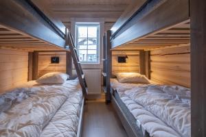 two bunk beds in a room with wooden walls at Exklusiv ski in-ski out stuga, i Hundfjället Sälen in Sälen