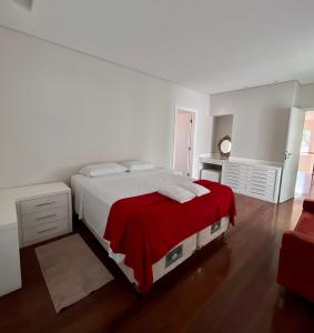 um quarto branco com uma cama grande e um cobertor vermelho em Casa alto padrão em Socorro em Socorro