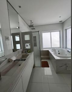 uma casa de banho branca com um lavatório, uma banheira e um espelho. em Casa alto padrão em Socorro em Socorro