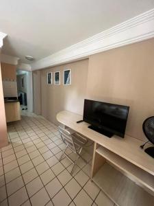 a living room with a desk with a flat screen tv at Boa Viagem Flat in Recife