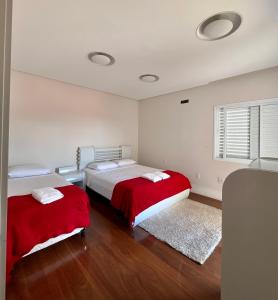 um quarto com duas camas com capas vermelhas em Casa alto padrão em Socorro em Socorro