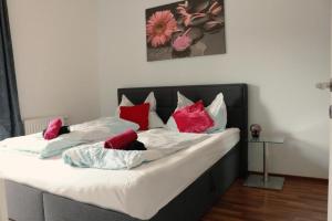 ein Bett mit roten und weißen Kissen darauf in der Unterkunft Aparthotel Vienna Airport in Himberg