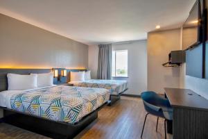 a hotel room with two beds and a desk at Motel 6-Harlingen, TX in Harlingen