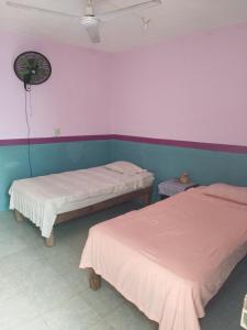 two beds in a room with pink and blue walls at Hostal y Temazcal Guemez in Pisté