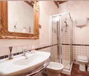bagno con lavandino, servizi igienici e specchio di Guesthouse da Idolina dal 1946 a Montalcino