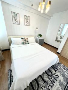 een slaapkamer met een groot wit bed en een tapijt bij Lancris Residences 2 Bedroom Entire Apartment near Airport with Pool in Manilla
