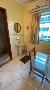 a bathroom with a table and a sink and a toilet at Pousada Emaús in Cruzeiro