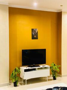 sala de estar con TV y pared amarilla en شقه مفروشه للإيجار تفرعات شارع مكرم عبيد مدينه نصر, en El Cairo
