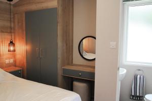 a bedroom with a mirror and a sink and a bed at Luxury 2-Bed Holiday Lodge near Bude & Widemouth in Holsworthy