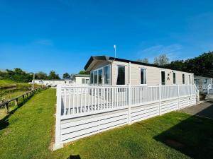 a house with a white fence in the grass at Luxury 2-Bed Holiday Lodge near Bude & Widemouth in Holsworthy