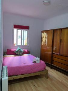1 dormitorio con cama con sábanas rosas y ventana en aparment puerto Alto en Madrid